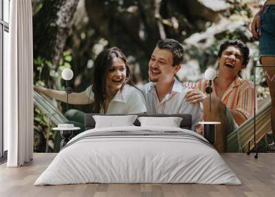 A joyful group of friends laughing together on a hammock in a sunny outdoor setting, enjoying friendship and leisure time. Wall mural