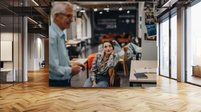 A student attentively listens to an elderly professor in a contemporary classroom environment, fostering learning and inspiration through inter generational exchange. Wall mural