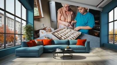 An elderly woman and a young boy bake pastries together in a cozy home kitchen, showcasing a warm family bond and the joy of cooking. Wall mural