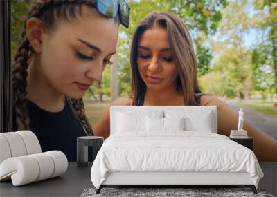 Closeup image of two young girls smiling and looking at their mobile phone Wall mural