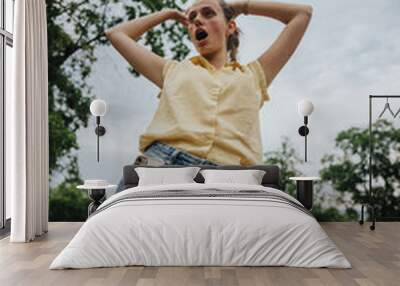 Girl having fun alone in the park with a playful and carefree attitude on a cloudy day Wall mural