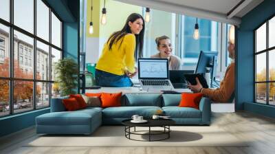 Group of professional coworkers ( team ) working on a desk in a modern office on their laptops while talking to each other. Business photo. Wall mural