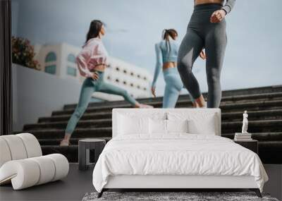 Low angle view of two active women in athletic wear running up staircase outdoors, focused on healthy lifestyle and fitness training. Wall mural