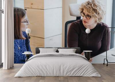 Professional women engaged in serious discussion at office table. Wall mural