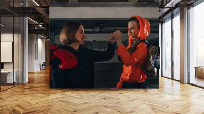 Profile pricture of two happy women boxer friends smiling and making high five before workout Wall mural