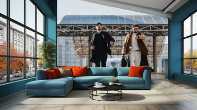 Shot captures two stylish men in motion, exuding confidence and dressed in modern business attire against an urban backdrop. Wall mural