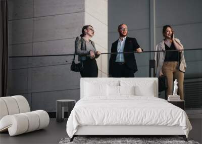 Three business professionals discuss and strategize on a modern balcony, showcasing teamwork and corporate collaboration. Wall mural