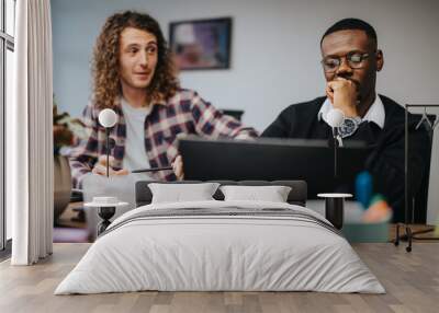 Two male office workers intensely discussing project ideas in a casual office setting, demonstrating teamwork and collaboration. Wall mural