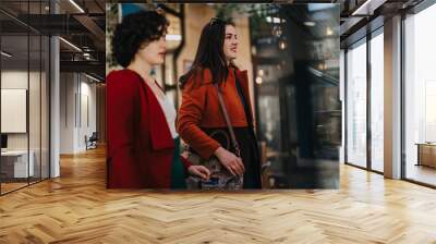 Two professional businesswomen engaged in an informal meeting outside, conveying collaboration and discussion. Wall mural