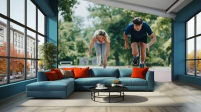 Two young athletes in a starting position, getting ready to run outdoors on a sunny day, showcasing determination and fitness. Wall mural