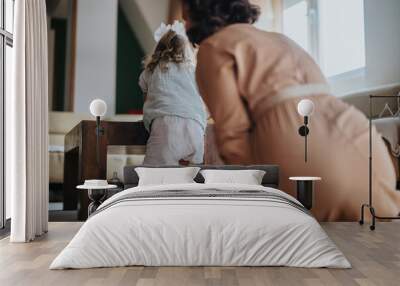 Warm and candid moment of a mother playing with her daughter in a comfortable home setting. The scene captures familial love and bonding. Wall mural