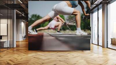 Women stretching in an outdoor park, wearing athletic wear and sneakers. Engaging in fitness and exercise routines on a sunny day. Wall mural