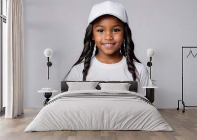 Little black girl wearing white t-shirt and white baseball cap isolated on grey background Wall mural