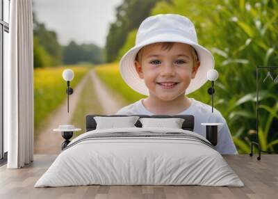 Little boy wearing white t-shirt and white bucket hat standing in nature Wall mural