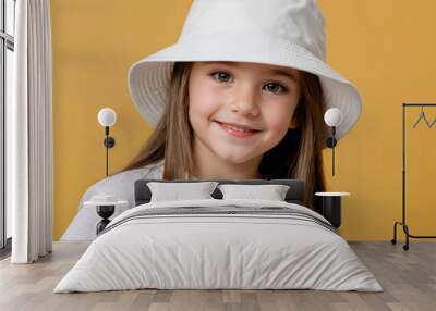 Little girl wearing white t-shirt and white bucket hat isolated on yellow background Wall mural