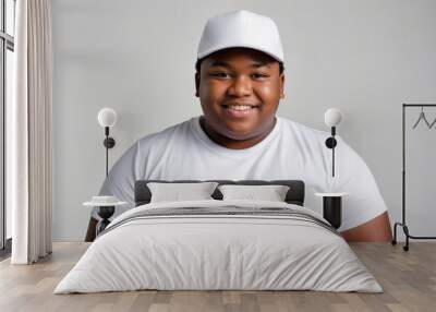 Plus size black teenage boy wearing white t-shirt and white baseball cap isolated on grey background Wall mural