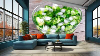 Blanched broccoli cabbage cooling down in icy water in a bowl on table Wall mural