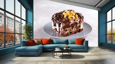 Dessert, sliced homemade cake with chocolate biscuit, raisins and cream of sour cream and whipped cream on a white plate on a concrete background. Wall mural