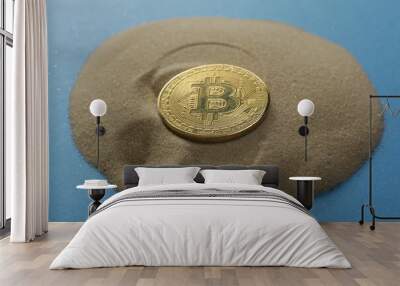 One bitcoin coin on the sand on a blue background Wall mural