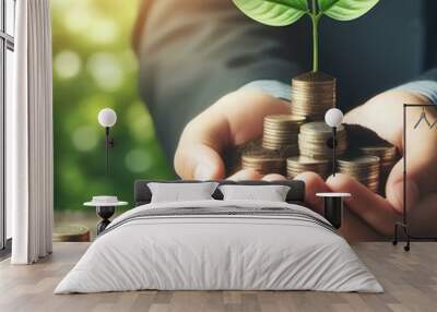 A hand holding a plant growing from coins, symbolizing economic growth and investment. Wall mural