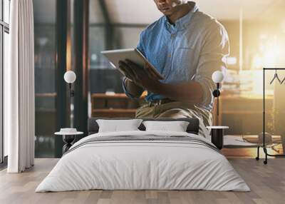 While others are dreaming hes making the dream work. Shot of a young businessman using a digital tablet during a late night in a modern office. Wall mural