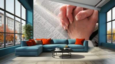 Female hands clasped in prayer ove a Bible Wall mural