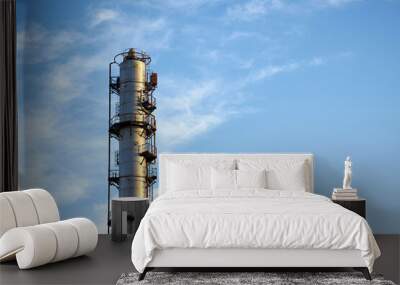 Old distillation column towers with blue sky with clouds background at chemical plant. Exterior of silver metal rusty methanol distillation enterprise with copyspace . Wall mural