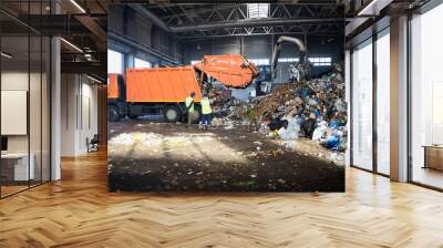 Two workers of recycling plant control process of unloading garbage from garbage truck Wall mural