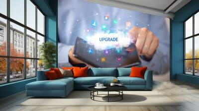 Businessman holding a foldable smartphone with UPGRADE inscription, technology concept Wall mural