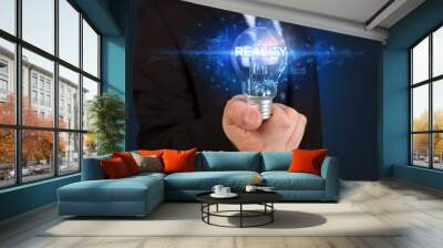 Businessman holding light bulb with REALITY inscription, innovative technology concept Wall mural