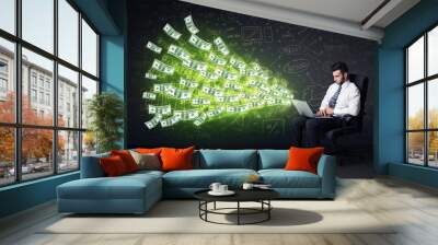 Businessman sitting in chair holding laptop with dollar bills co Wall mural