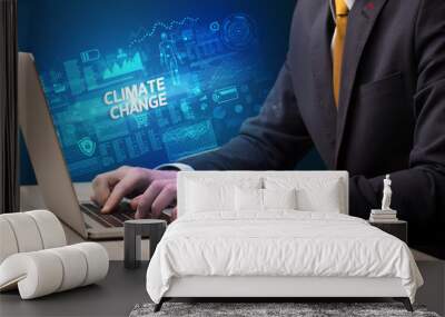 Businessman working on laptop with CLIMATE CHANGE inscription, cyber technology concept Wall mural