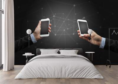 close up of two hands holding smartphones to each other, wireless connection concept Wall mural