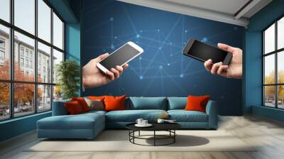 Close up of two hands holding smartphones to each other, wireless connection concept Wall mural