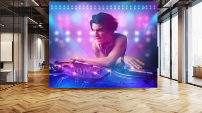 Disc jockey mixing music on turntables on stage with lights and Wall mural