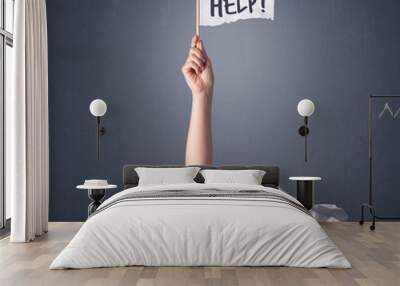 Female hand emerging from crumpled paper pile holding a white flag with help written on it Wall mural