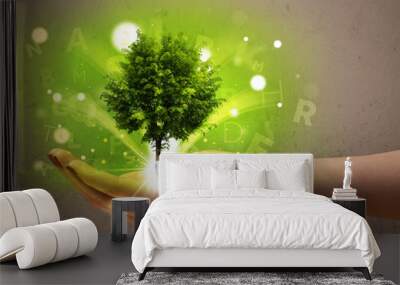 Glowing tree growing in the hand of a woman Wall mural