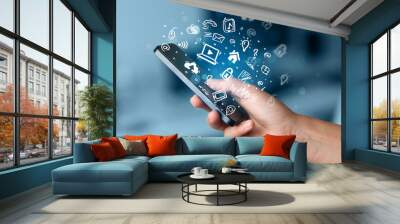 Hand holding smartphone with media icons and symbol Wall mural