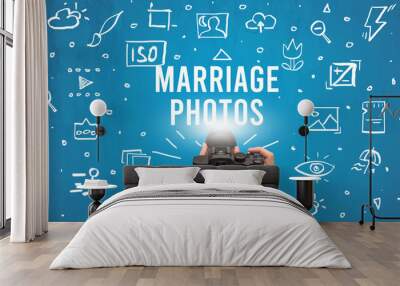 Hand taking picture with digital camera and MARRIAGE PHOTOS inscription, camera settings concept Wall mural