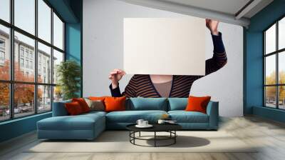 woman holding in front of her head a paper with copy space Wall mural