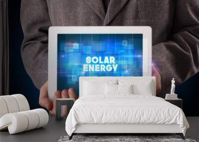 Young business person working on tablet and shows the inscription: SOLAR ENERGY Wall mural