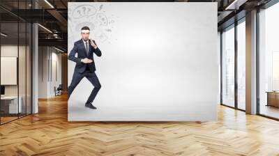 Young businessman in suit fighting with doodled symbols concept
 Wall mural