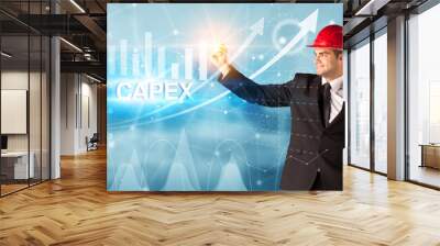 Young businessman with helmet drawing CAPEX inscription, modern business technology concept Wall mural