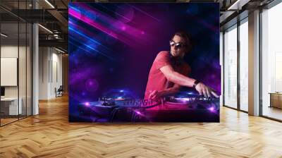 Young DJ playing on turntables with color light effects Wall mural