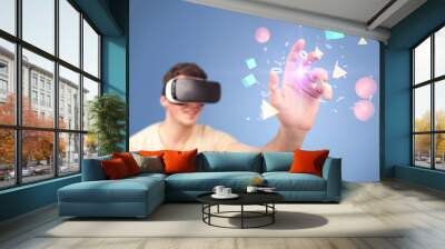 Young impressed man wearing virtual reality goggles with geometric shapes around his hand Wall mural