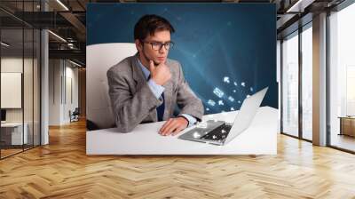 Young man sitting at dest and typing on laptop with message icon Wall mural