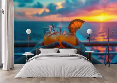 Two glasses of orange juice clink with tropical sea and sunset romantic background Wall mural