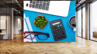 Investment, finance and work concept with charts and graphs and laptop, coffee, calculator on blue board flat lay Wall mural