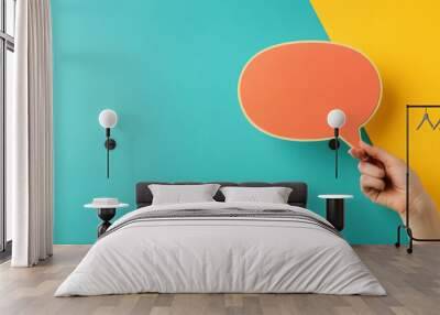 A hand holding a speech bubble, representing communication and sharing information on social media.  The colorful design reflects a modern and playful style. Wall mural