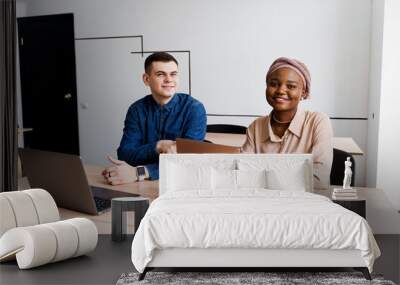 Muslim black girl and white man with laptop. Multiethnic couple work online together on business project. Working at home. Surfing internet Wall mural